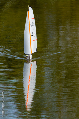 Remote controlled yacht sailing on a suburban lake.