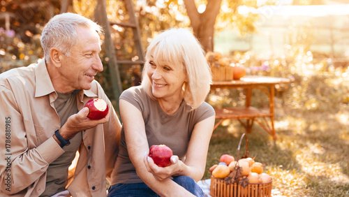 Foto An elderly couple smiles at each other while holding apples in a beautiful garden