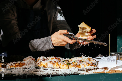 Parmesan Cheese in Hand Being Grated Over Pizza at Restaurant