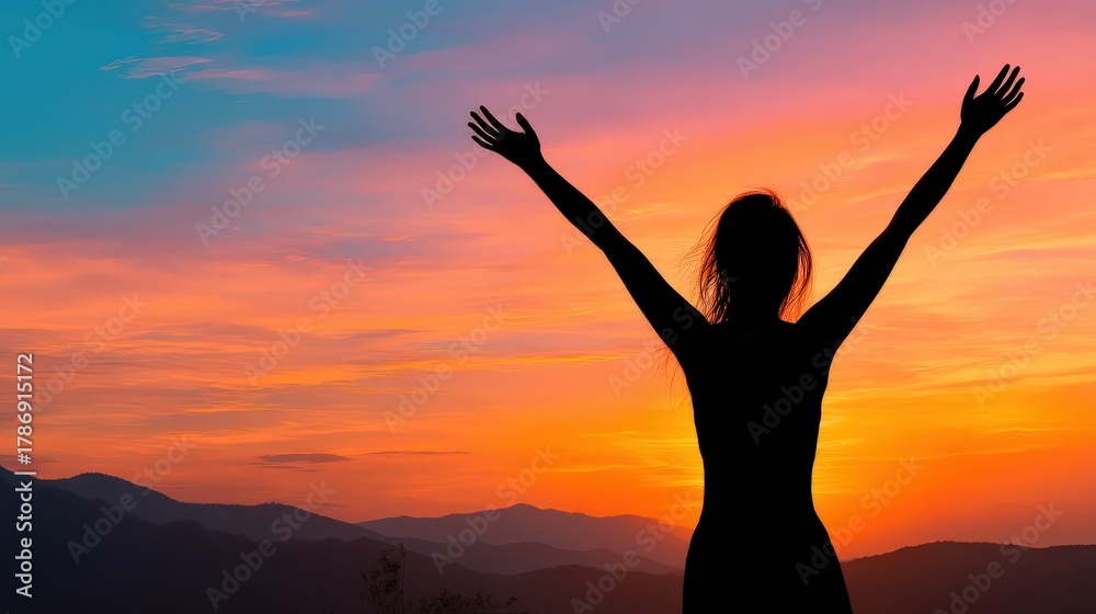 Fototapeta premium A silhouette of a woman with arms raised against a vibrant sunset, symbolizing freedom and joy in a serene landscape.