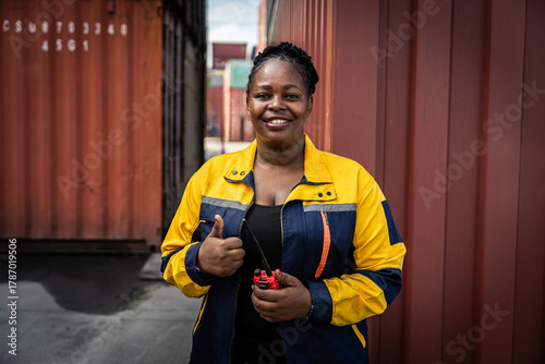 Tableau sur toile A woman wearing a yellow and blue jacket is smiling and holding a remote control