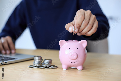 Businessman holding coins putting in pink piggy , Planning step up, saving money for future plan .