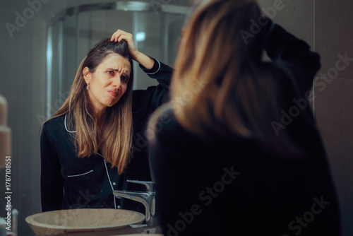 Papier peint Woman Looking in the Mirror Checking the Roots of her Hair