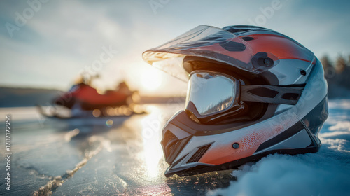 Winter snowmobile helmet with tinted visor on frozen lake surface at sunset, extreme cold weather adventure scene
