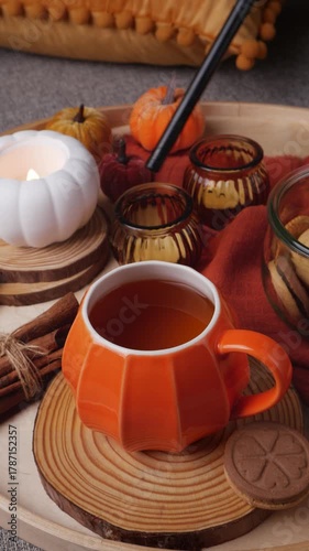 Lighting white pumpkin candle on wooden tray—cozy autumn home decor with cookies and amber glass. Female hand lights a pumpkin-shaped candle on wood slices amid velvet minis, cookies and warm textiles