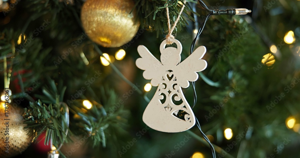 Obraz premium Christmas, decoration and festive with angel on tree in home for celebration, event or tradition. Background, holiday and wallpaper with ornament in apartment for aesthetic, vacation or winter season