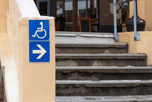 Accessibility sign pointing right next to stairs