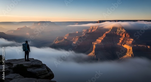 Lone hiker stands atop foggy canyon at sunrise — Digital detox wilderness retreat for awe-filled solitude and horizon gazing Stock royalty free