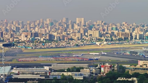 Cinematic 4K aerial drone shot with truck right slider movement showing Mumbai airport runway and dense city skyline on a bright clear day.