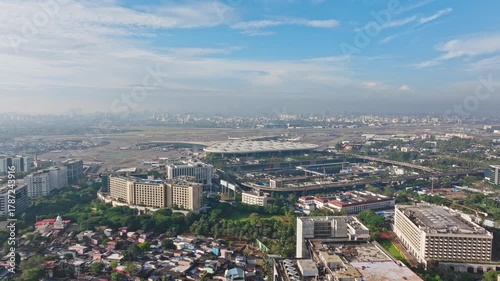 Cinematic 4K aerial dolly-in drone shot of Mumbai International Airport with city skyline in the background under a bright blue sky on a clear day