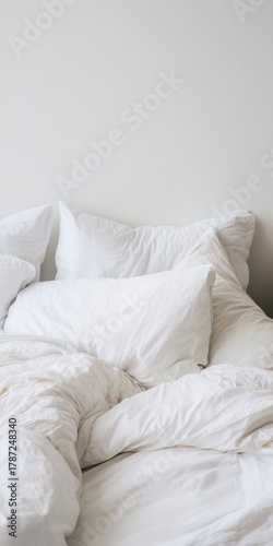 Unmade bed with white pillows and duvet in bedroom