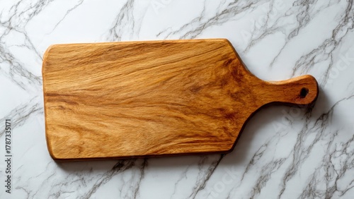 Empty wooden charcuterie board on white marble surface. Elegant arrangement suggests future use. Soft shadows and clean composition