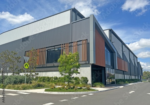 Corner of a modern warehouse unit complex with a foot path, garden and road
