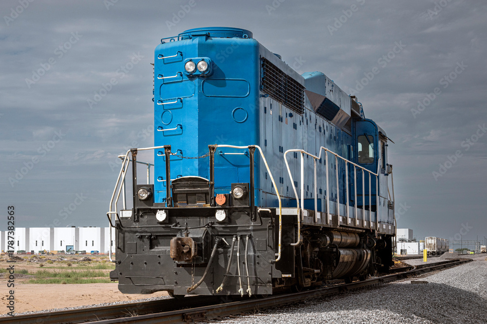 Obraz premium A train engine on tracks leading to industry in background