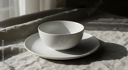 Minimalist White Ceramic Bowl and Plate on Textured Fabric with Natural Shadows