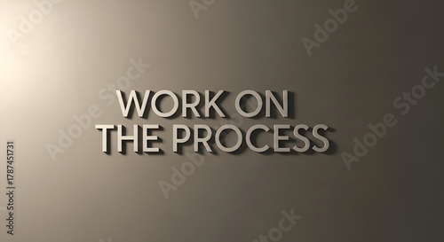Motivational wall art displaying the phrase 'Work on the process' in bold, three-dimensional letters on a neutral-colored wall to inspire productivity and focus