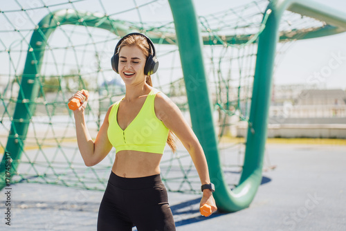 Konstfotografi Dancing to the rhythm, a woman enjoys her workout with headphones on, feeling energized and cheerful amidst a vibrant playground setting