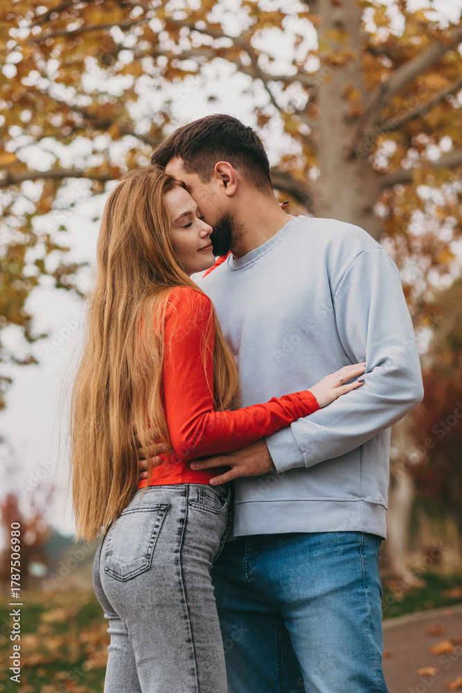 Fototapeta premium Couple sharing tender moment amidst colorful autumn leaves scene