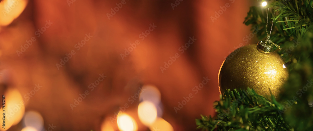 Fototapeta premium Golden Christmas bauble upon green tree branches featuring warm festive lights glowing softly within background