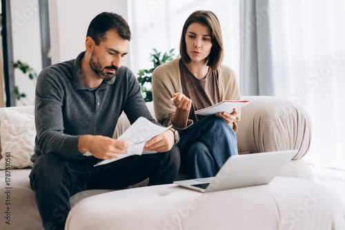 Couple managing finances at home reviewing bills and laptop