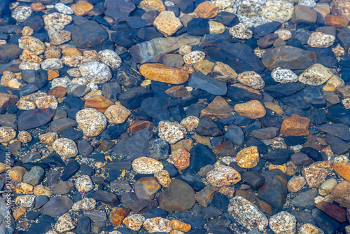 Small multi-colored stones in clear water at the bottom of a mountain lake