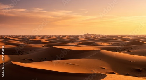 Fototapeta Naklejka Na Ścianę i Meble -  Vast desert landscape with sand dunes under a warm sunset sky evoking themes of adventure and exploration