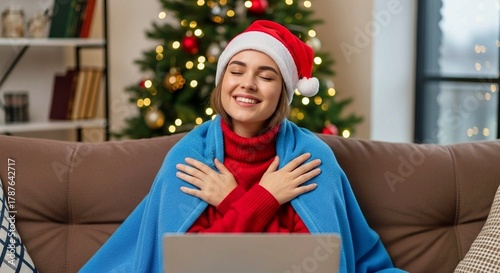 Joyful Woman in Santa Hat Relaxing with Laptop by Christmas Tree – Cozy Holiday Home Scene