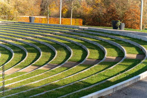 Curved amphitheater steps sweep in repeating lines of concrete and grass. Long shadows add rhythm to the minimalist scene.