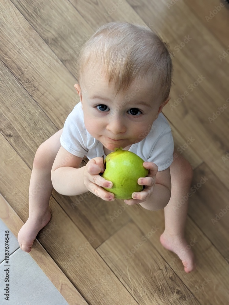 Fototapeta premium A confident baby sitting independently and holding a colorful ball, mastering a new skill.