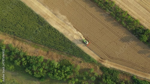 Above top view, dolly move over, follow agricultural harvester, combine as he cutting and harvesting mature wheat on farmland. Harvest time in summer, season. 