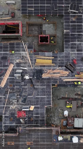 High-angle drone image showing a large-scale construction site with workers, scaffolding, rebar, formwork, and materials during the concrete framework phase of a multi-story building.