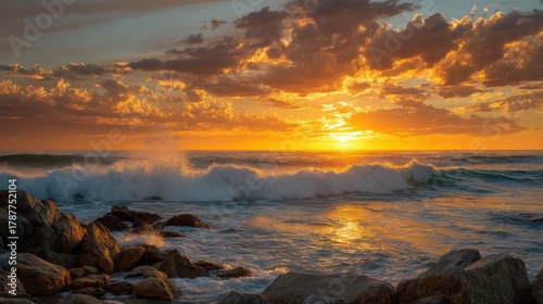 Vibrant sunset over the ocean casting a warm golden glow on a rocky shoreline