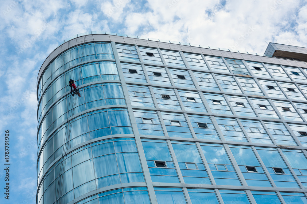 Fototapeta premium Curved Glass Facade with Window Cleaner - Urban Rope Access Scene
