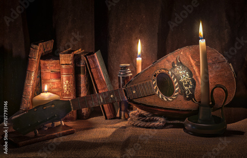 Old broken mandolin lit by candlelight with old books