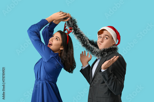 Young couple with Christmas tinsel on blue background