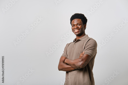 Confident young adult black man smiling with arms crossed looking at camera