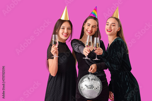 Beautiful young women with champagne and disco ball on purple background. New...