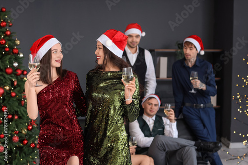 Female coworkers with champagne celebrating New Year at corporate party in of...