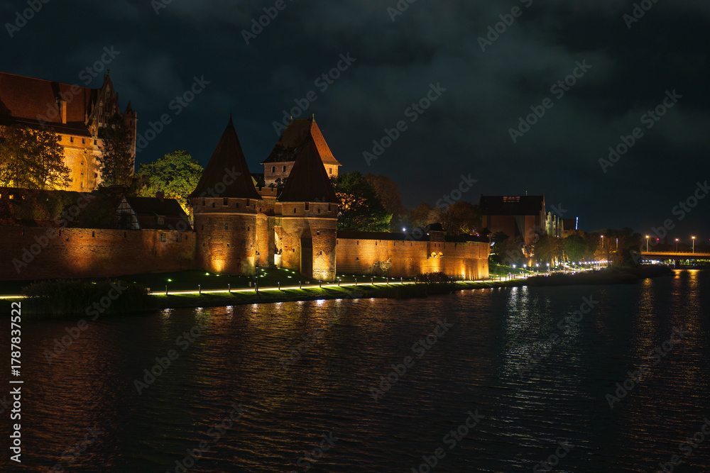 Fototapeta premium Malbork Castle at night along the Nogat River in Poland