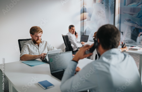 Canvas Print A bustling office scene with colleagues using laptops, tablets, and phones