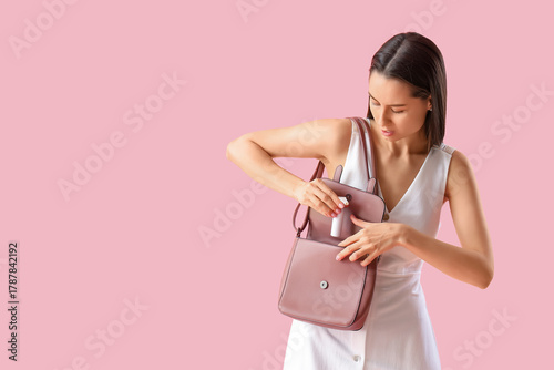 Young woman putting spray f...