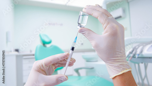Dentist hands in gloves preparing local anesthesia injection with syringe and medicine vial for dental treatment in a blurred modern clinic background