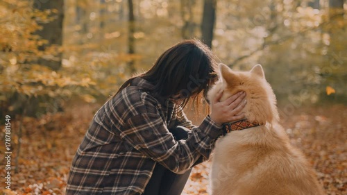 young woman walking and playing with her japanese akita puppy in autumn forest
