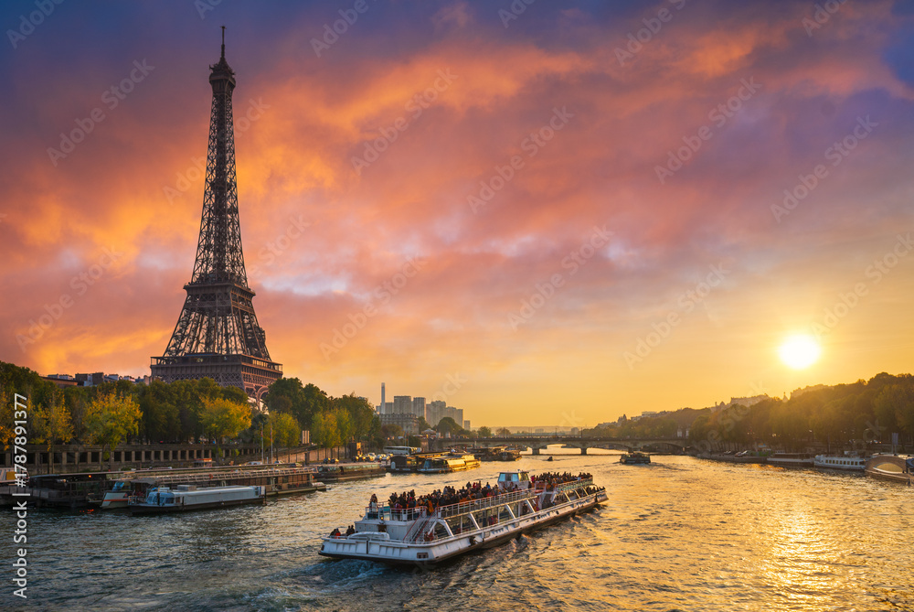 Fototapeta premium Sunset at the Eiffel tower, Paris, France with a tourist boat