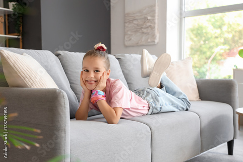 Little girl lying on sofa a...