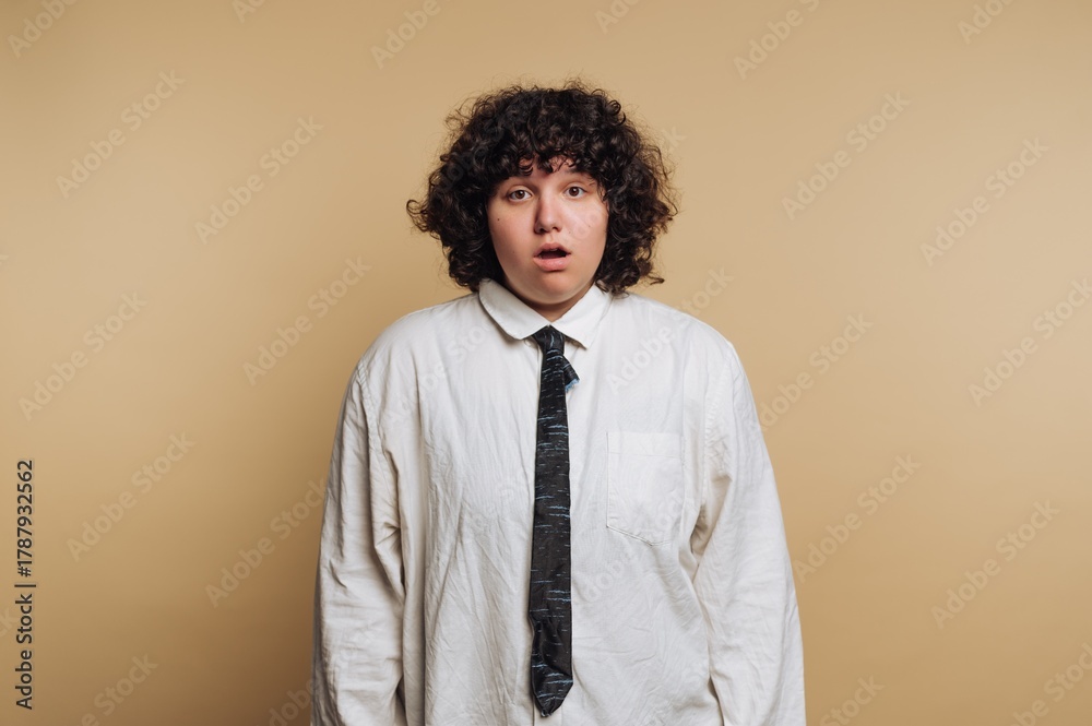 Obraz premium Surprise expression on a person's face with curly hair against a plain background during a casual indoor setting