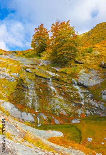 Monte Gorzano, Italy - The highest peak in the mountain range named Monti della Laga, with Cento Fonti waterfalls and hikers who practice trekking in altitude, in autumn with foliage