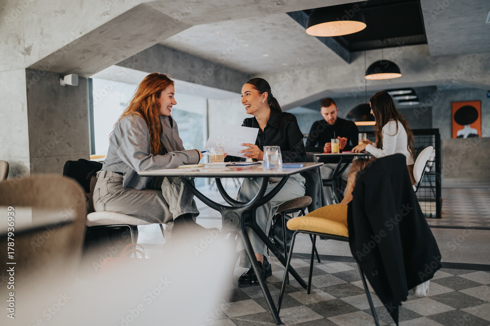 © qunica.com - A group of coworkers and friends discuss documents around a round table in a stylish cafe. Warm, collaborative atmosphere with modern design and relaxed teamwork.