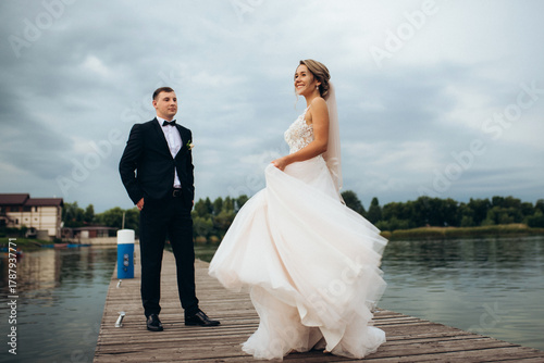 young couple, the bride and groom, walking along a pier