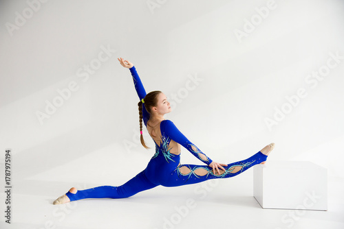 young woman in blue acrobatic suit doing yoga exercise.  Sport  conception. Split